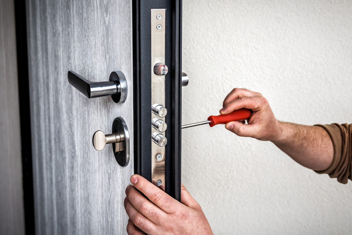 Professional locksmith repairing the door lock in metal entrance door