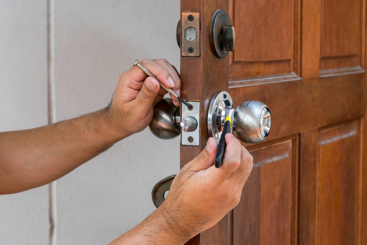 locksmith working on a silver lock on a wooden door